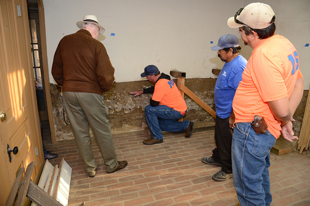 Image of workman remove lower plaster in the the Adobe to examine the condition of adobe blocks and decide which ones need replacement. Photo by Raymond Kwan, 2016.